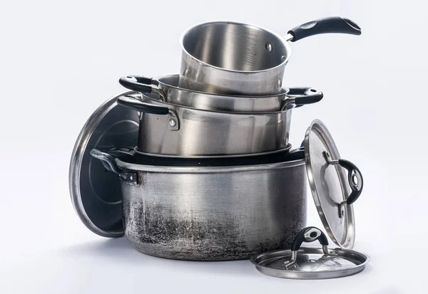 Mutfakta kullanılan tencere ve kapaklar, beyaz arka planda üst üste dizilmiş..