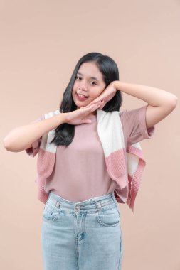 Çekici bir gülümseme ve el hareketleriyle Asyalı bir kadın. Pastel bir kıyafet, kot ve kazak giyiyor. Neşeli bir ifade ve modern bir moda sergiliyor..