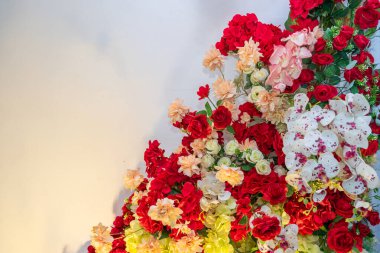 Kırmızı güller, beyaz orkideler ve yeşil yapraklı şeftali çiçekleri. Dekorasyon, düğün, tebrik kartı ve yaratıcı tasarım için mükemmel..