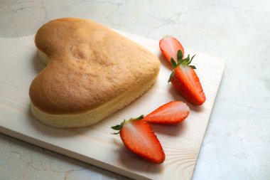 Sevgililer günü için ahşap doğrama tahtasında çilek ile kalp şekli peynir pastası