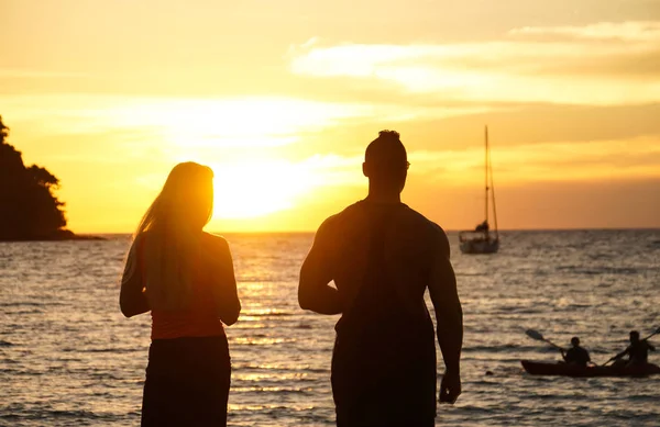 a couple stand watch sunset take photo by the beach