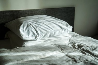 bir otel odasında dağınık yatak, çarşaf ve yastık