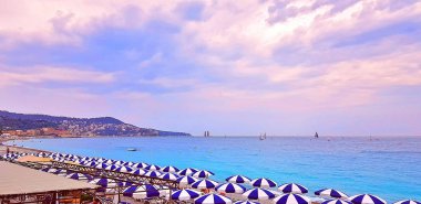 Çok renkli şemsiye plajda Nice ve turkuaz su Cote d'Azur, Fransa sakin. Deniz günbatımı