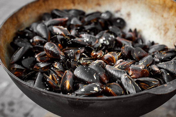 The process of preparing mussels in a large saucepan. Street food with seafood.