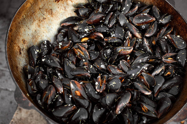 The process of preparing mussels in a large saucepan. Street food with seafood.