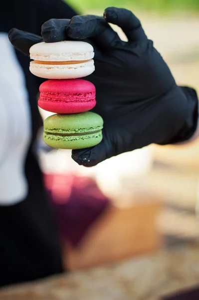 Multicolored macaroons in the hand of the pastry-cook.