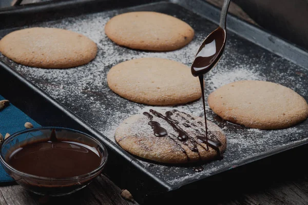 Hot baked goods. Cookies on a baking sheet. Caramel pours from the spoon on the biscuits.