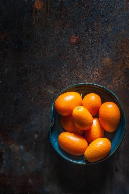 Kamkat meyve karanlık bir arka plan üzerinde siyah seramik plaka üzerinde