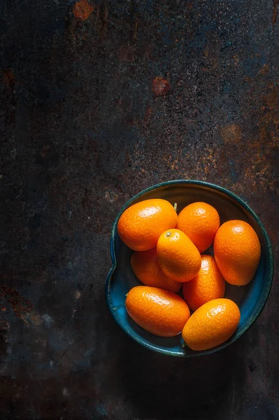 Kamkat meyve karanlık bir arka plan üzerinde siyah seramik plaka üzerinde