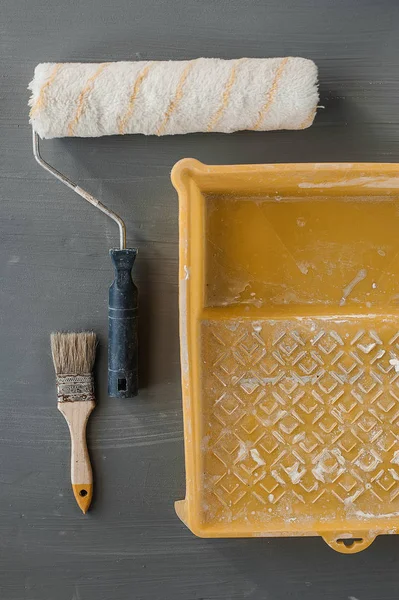Rullo, spazzola e secchio usati per dipingere sullo sfondo . — Foto Stock