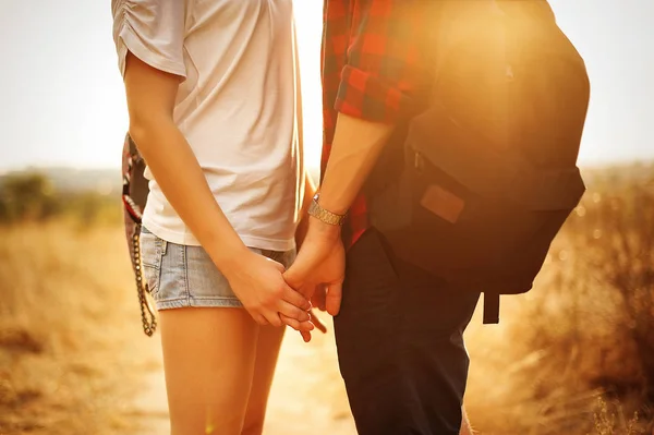 Aşık bir çift el ele tutuşsun batan güneşin ışınları. Görünümü kapatın