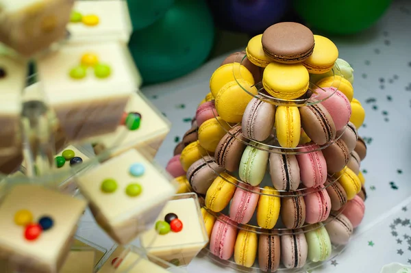 Mousse em óculos e macarons franceses coloridos pirâmide bolo multinível no carrinho de sobremesa de plástico . — Fotografia de Stock