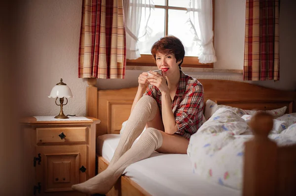 The girl drinks coffee in bed. Morning. Rustic interior