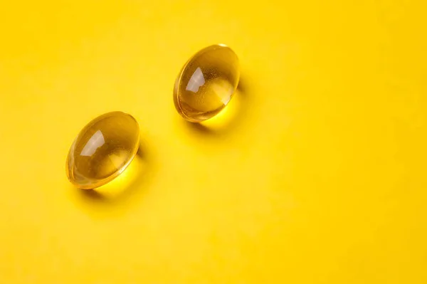 黄色の透明な魚の油の丸薬は黄色の背景で — ストック写真