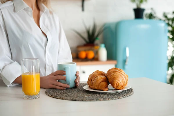 Vrouw in wit overhemd drinken koffie met croissants — Stockfoto