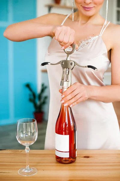 Ragazza apre una bottiglia di vino con un cavatappi — Foto Stock