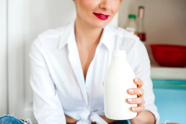 Woman holding a bottle of yogurt near the fridge — Stock Photo, Image