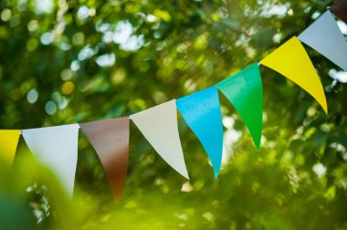 Ağaçtaki kağıt bayrakların çelengi. Arka planda yeşil yapraklar