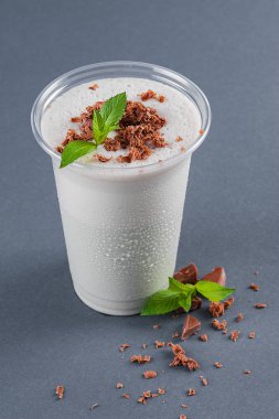 Gri bir arka plan üzerinde nane ve çikolata parçaları ile Milkshake