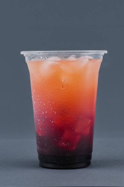 Gri bir arka plan üzerinde şurup ve buz küpleri ile soğuk içecek