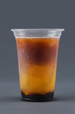 Gri bir arka plan üzerinde kahve, portakal suyu ve buz küpleri ile soğuk içecek