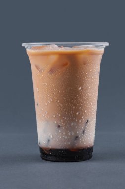 Gri bir arka plan üzerinde kahve, süt ve buz küpleri ile soğuk içecek