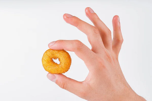 Маленький пончик в мужской руке на белом фоне — стоковое фото