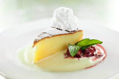 Kremalı sos ve meyveli bir tabakta cheesecake servisi. Yumuşak odak