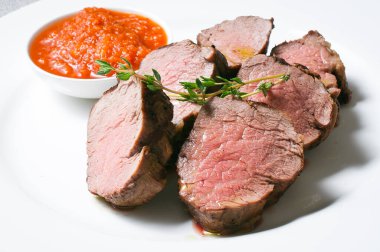 Beyaz tabakta domates soslu sulu biftek..