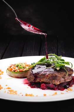 Böğürtlen soslu et ve beyaz tabakta sebze