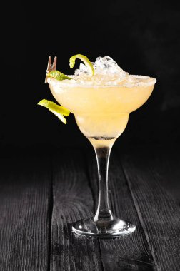 Alkolik, alkolsüz, siyah arka planda buzlu sarı kokteyl.