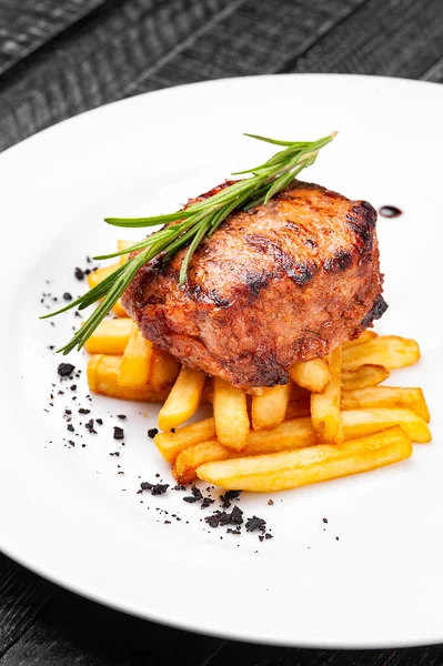 Medalhão de bife com batatas fritas em um prato branco . — Fotografia de Stock