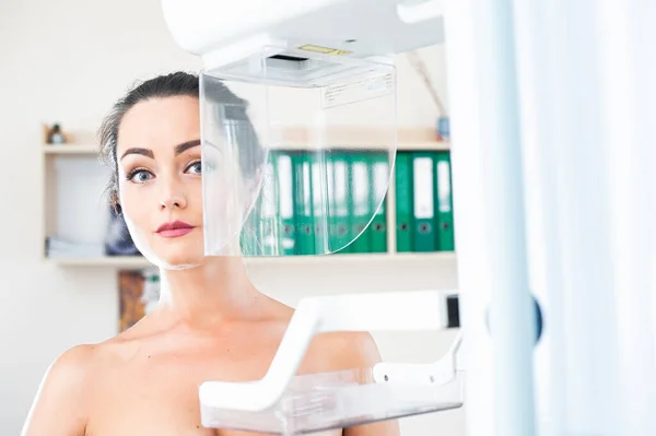 Young woman at breast cancer prevention screening at hospital. Hardware examination of the breast. Healthy young woman doing cancer prophylactic mammography scan. Modern hospital with hi-tech machine