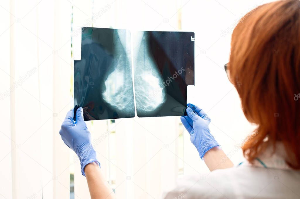 The doctor looks at the x-ray of the female mammary glands. Hardware examination of the breast.