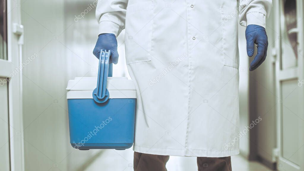 Medical worker, nurse, doctor holding a portable refrigerator bag in the hospital.