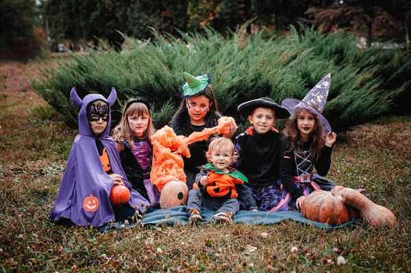 Дети Костюмах Хэллоуин Сидят Одеяле Тыквами Траве — стоковое фото