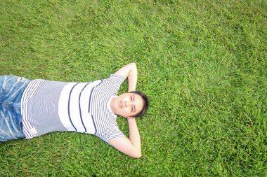 Genç adam doğanın tadını çıkarıyor. Çimlerin üzerinde uyuyor.