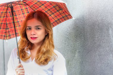 Kırmızı dudak ve kırmızı şemsiye tutan sarı saçlı Tay güzel bayan Portresi