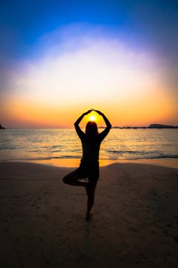 Gün batımında sahilde siluet kadın yoga