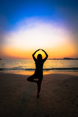 Gün batımında sahilde siluet kadın yoga