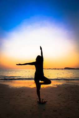 Gün batımında sahilde siluet kadın yoga