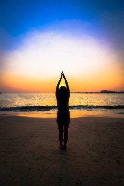 Gün batımında sahilde siluet kadın yoga