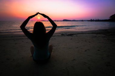 Gün batımında sahilde siluet kadın yoga