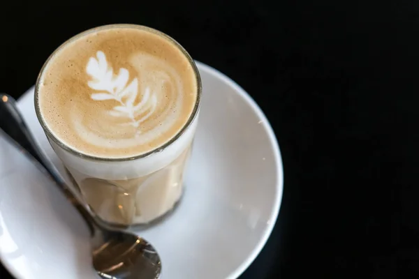 cup of the latte art coffee on the black table with copy space