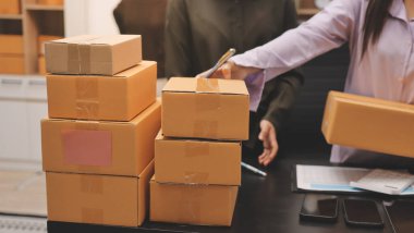 Küçük işletmeler kurma portresi KOBİ sahipleri ve iki Asyalı kadın online siparişleri kontrol ediyor. Ev işlerinde çalışan kutucuklarla çalışan ürünleri satıyorlar.