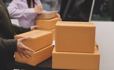 Küçük işletmeler kurma portresi KOBİ sahipleri ve iki Asyalı kadın online siparişleri kontrol ediyor. Ev işlerinde çalışan kutucuklarla çalışan ürünleri satıyorlar.