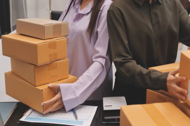 Küçük işletmeler kurma portresi KOBİ sahipleri ve iki Asyalı kadın online siparişleri kontrol ediyor. Ev işlerinde çalışan kutucuklarla çalışan ürünleri satıyorlar.