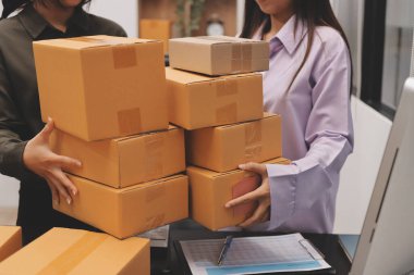 Küçük işletmeler kurma portresi KOBİ sahipleri ve iki Asyalı kadın online siparişleri kontrol ediyor. Ev işlerinde çalışan kutucuklarla çalışan ürünleri satıyorlar.