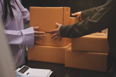 Küçük işletmeler kurma portresi KOBİ sahipleri ve iki Asyalı kadın online siparişleri kontrol ediyor. Ev işlerinde çalışan kutucuklarla çalışan ürünleri satıyorlar.