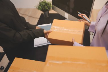 Küçük işletmeler kurma portresi KOBİ sahipleri ve iki Asyalı kadın online siparişleri kontrol ediyor. Ev işlerinde çalışan kutucuklarla çalışan ürünleri satıyorlar.